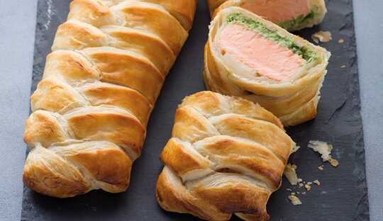 Picture of salmon, rolled with herbs in a Wewalka puff pastry-dough, already baked and sliced in pieces put on a granite platter